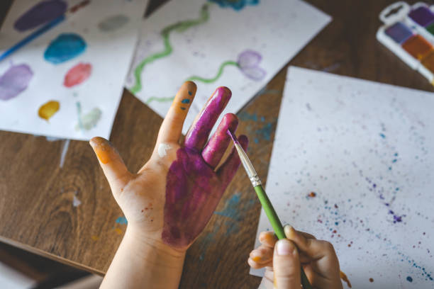 Children’s drawing workshop, happy children make handprints with paint.